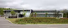 Rectangular windowed building, with landscaping and a sign in front labeled 'Lexus'.