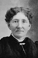 Photograph of woman with short wavy hair, looking straight into camera