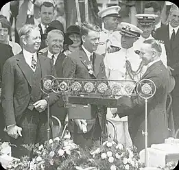 Lindbergh looks on as President Calvin Coolidge presents her son with the Distinguished Flying Cross (June 11, 1927)