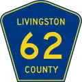 A blue pentagon with a yellow border and three lines of yellow text, reading Livingston County 62.