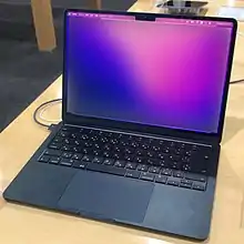 A MacBook Air, in midnight color, on a wooden desk.