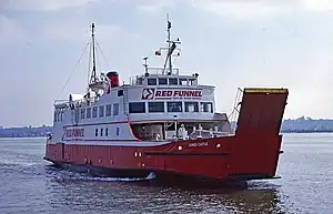 Three-quarter view of ship with red hull and white superstructure sailing from left to right.