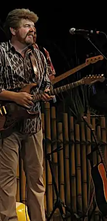 Mac McAnally standing on a stage and playing an electric guitar