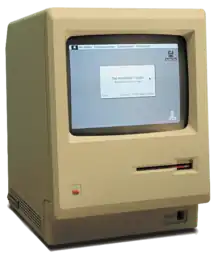 A beige, boxy computer with a small black and white screen showing a window and desktop with icons.