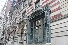 The ground-story windows on Madison Avenue. The window in the foreground is a rectangular metal-framed window which is divided into six panes by mullions and a transom bar.