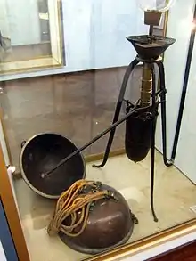 A glass display case holds a mechanical device with a lever arm, plus two metal hemispheres attached to draw ropes. (from Outer space)