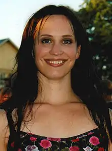 Picture of a 28-year-old woman with a black, open hair up to breast level and a wide smile