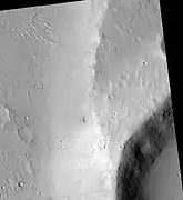 A streamlined island in the Maja Valles, as seen by HiRISE. The island formed behind the impact crater partially visible at lower right.