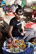 Young Balinese woman making canang to sell at the local pasar (market).