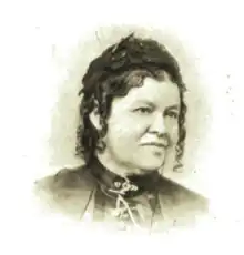 Black and white portrait photograph of a woman with hair in an up-do who is wearing a blouse with a high collar.