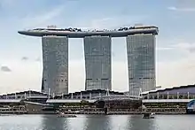 Three towers are joined by a terrace that stretches out between their respective roofs, protruding over the edge of each tower.