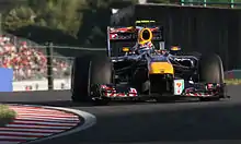 A navy-and-yellow single-seater racing car is driven around a tarmac course.