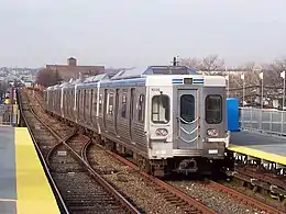 A silver subway train leaving a station