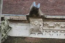 Detail of a sculpture known as a marmoset, a crouching figure with damaged lower body parts and a simple gargoyle above.