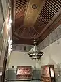 One of the chambers and exhibition rooms off the courtyard, with painted wood ceiling and stucco and zellij wall decoration