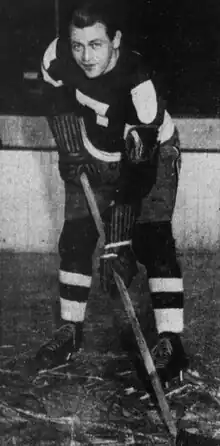 Black and white photo of a hockey player holding a hockey stick, in uniform with a number 7 on the front