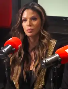 A 44-year-old black woman with long, brown hair and blonde streaks, looking at something to the left of the camera.