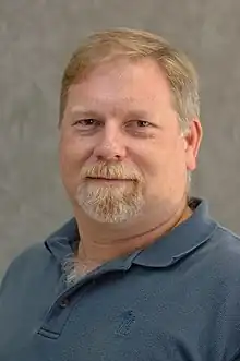 Light-heaired, goateed man in blue sports shirt