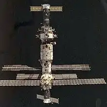 A spacecraft docked to the Mir space station, in front of a dark space background