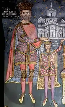 A bearded man and a boy (both wearing a crown) hold a church on their hands