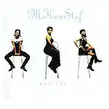 The cover consists of three women sitting on stools against a white background.