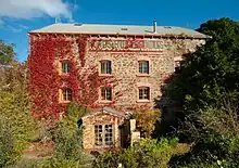 front of a three-story stone building partly covered in ivy