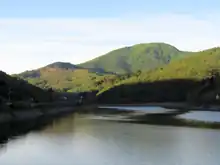 Photo shows a lake in the foreground and a mountain in the background.