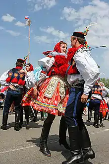 Young men and women in colourful, traditional dress dancing outdoors