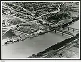 An aerial view of Murray Bridge in 1953 showing rail and road bridges, and also paddle steamers.