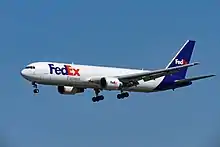 Side quarter view of twin-engine jetliner in flight, with extended gear