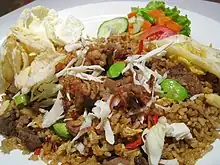 Nasi goreng with various condiments includes; emping cracker, fried shallots, acar pickles and lalab.