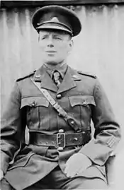 An informal portrait of a man in military uniform sitting down with his head cocked slightly to the side.