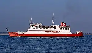 Broadside view of ship, with red hull and white superstructure, steaming right to left