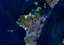 An indistinct image from space of brown and green islands in dark blue water.