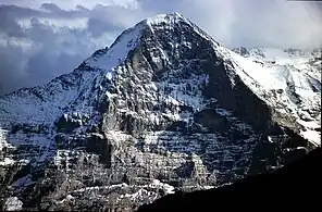 With sunlit snowfields and dark clouds in the distance