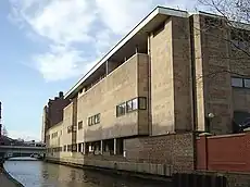 Low level view of a light coloured building alongside a canal