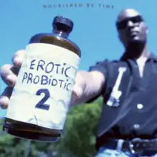 Brown holding a medicine bottle with a hand-written label that says "Erotic Probiotic 2" on it