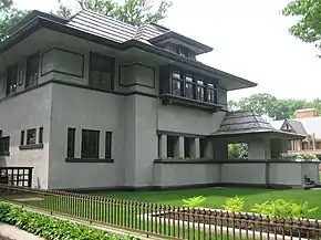 Recent exterior view of the house from the southeast corner.  The library windows are visible at left with the entrance porch at far right.  The living room planter with bedroom bay window are at center.  Deep eaves shade the house from the mid-day summer sun.