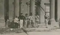 Marriott, fifth from left in stove pipe hat, holding his lapels, stands before the neo-classical (but wooden) Oddfellows Hall, 1860s