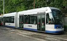 A white and blue low-floor light rail vehicle labeled "MOMO"