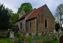 A flint church with a red tied roof and a tower at the west end, seen from the southeast