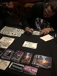 Orikal Uno doing custom graffiti stickers and selling his music at merchandise table