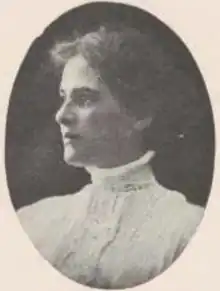 A young white woman wearing a high-collared white blouse with lace trim