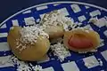 dumplings on a plate, one cut open to show fruit inside, all topped with cottage cheese