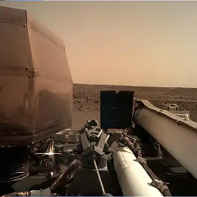 Image of the science deck of the InSight lander, with the Martian landscape in the background