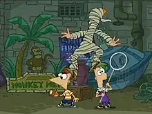 Two cartoon boys stand beside each other looking in opposite directions. A cartoon girl with orange hair stands clumsily on their heads, wrapped in raggy toilet paper. Behind them are pipes, a gray brick wall, and signs.