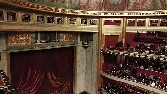 Decoration of the interior with ceiling mural and concrete tiers for seating, without pillars.