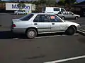 Late 80's Honda Accord with a sticker violation tag for illegal parking.