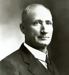 Clean shaven man with receding hairline in a coat and tie