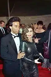 Paula Abdul modeling a semi-transparent black dress, curled hair and smoky eye makeup at the 62nd Academy Awards in 1990